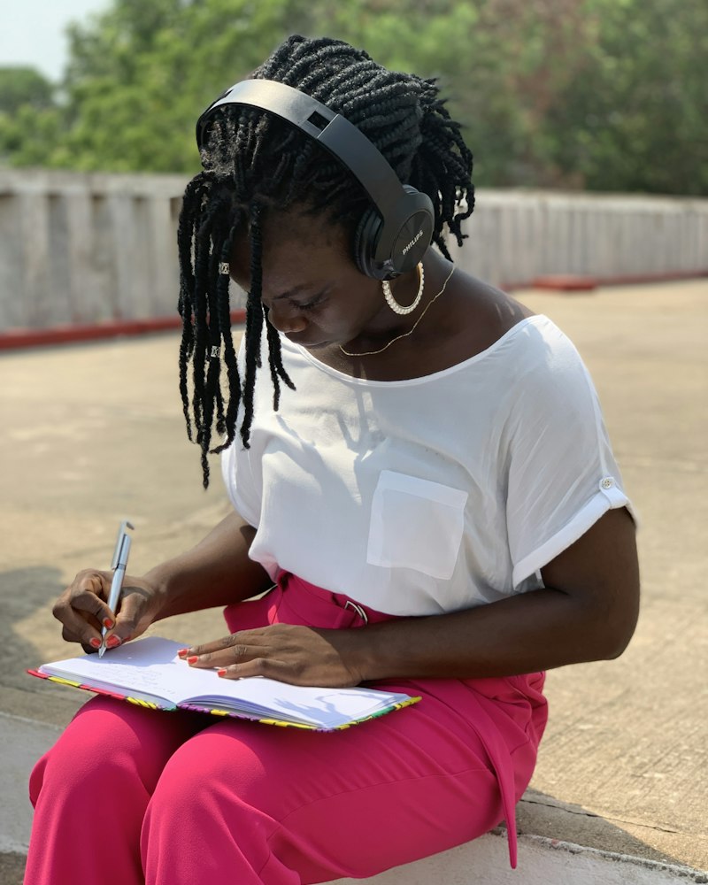 A woman sits outside writing in a notebook