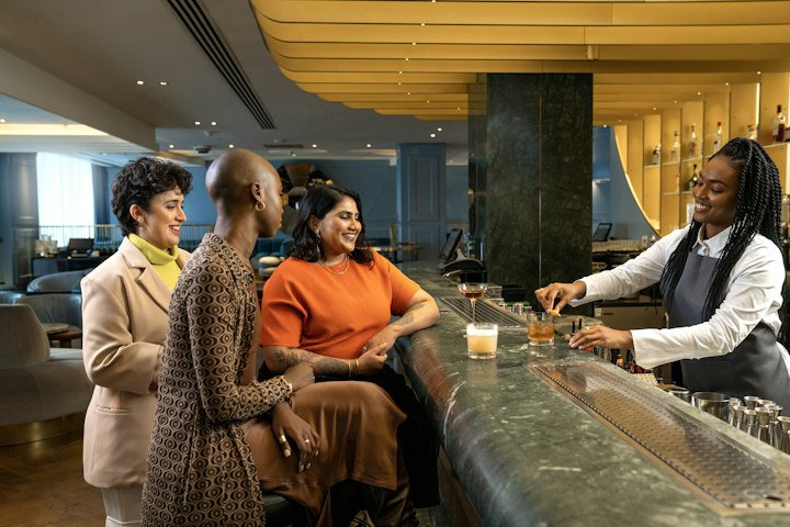 A bartender serves drinks to guests at a hotel bar